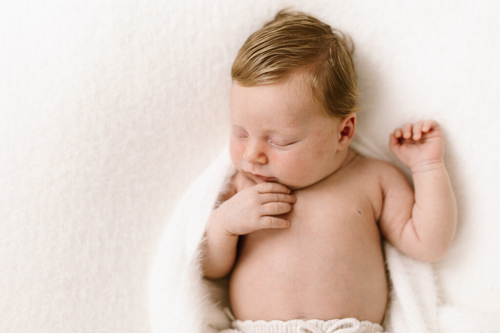 Close up of Sweet newborn asleep curled in a soft fluffy white blanket