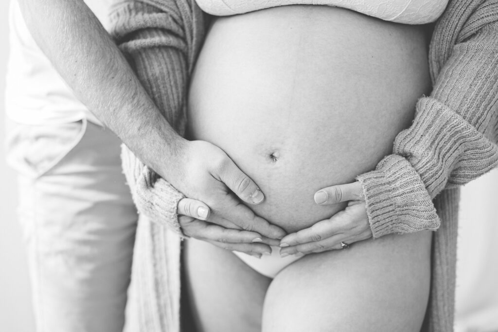 Pregnant tummy with mum and dad's hands cradling the bump