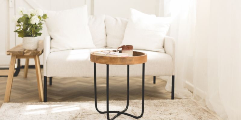 Beige sofa with side table and mug, soft natural light in studio space