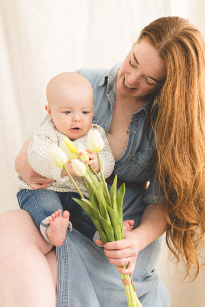 Baby grabbing bouquet of flowers on mum's lap