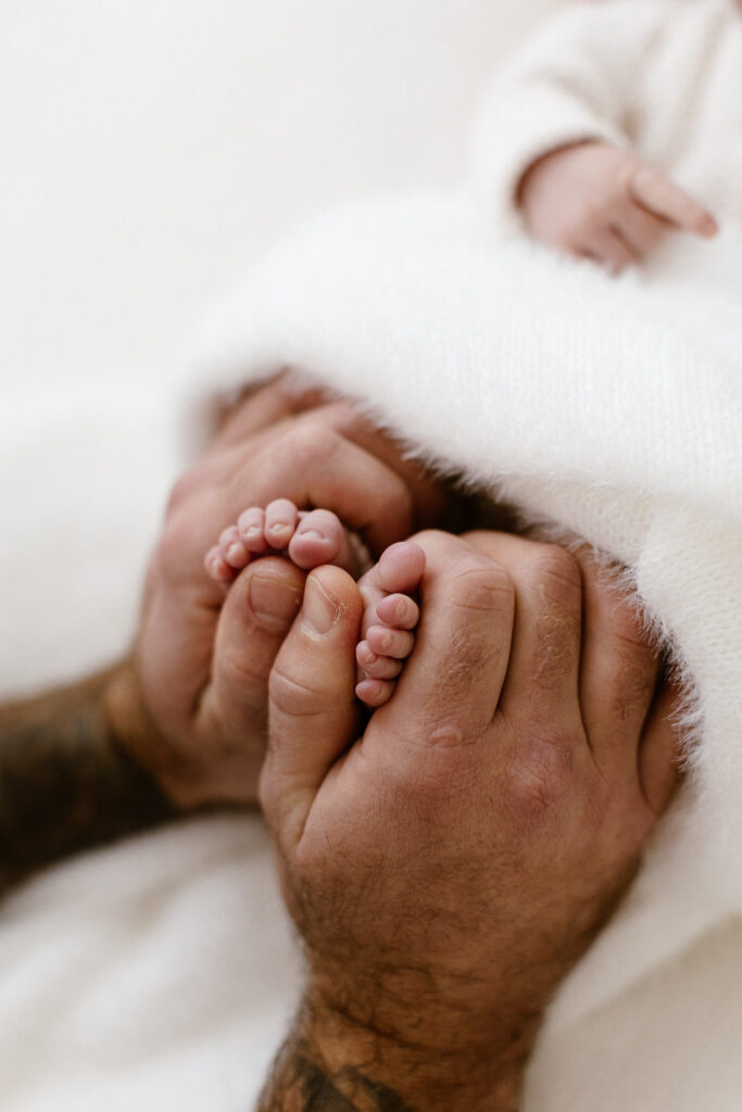 Dad's hands holding newborn toes