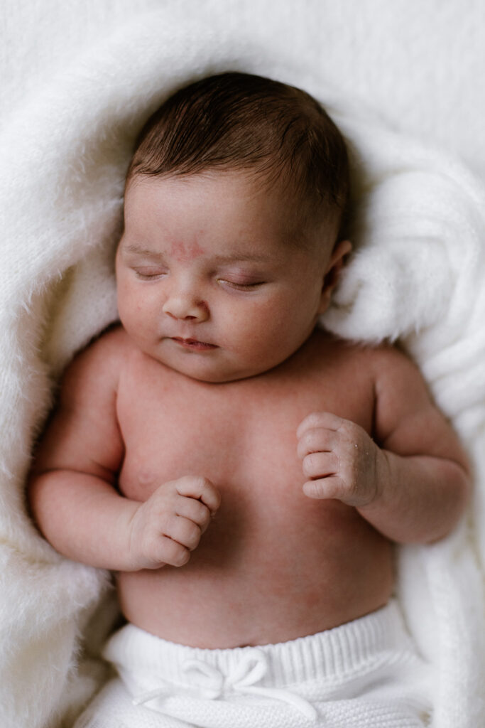 Newborn Baby asleep surrounded by soft blanket