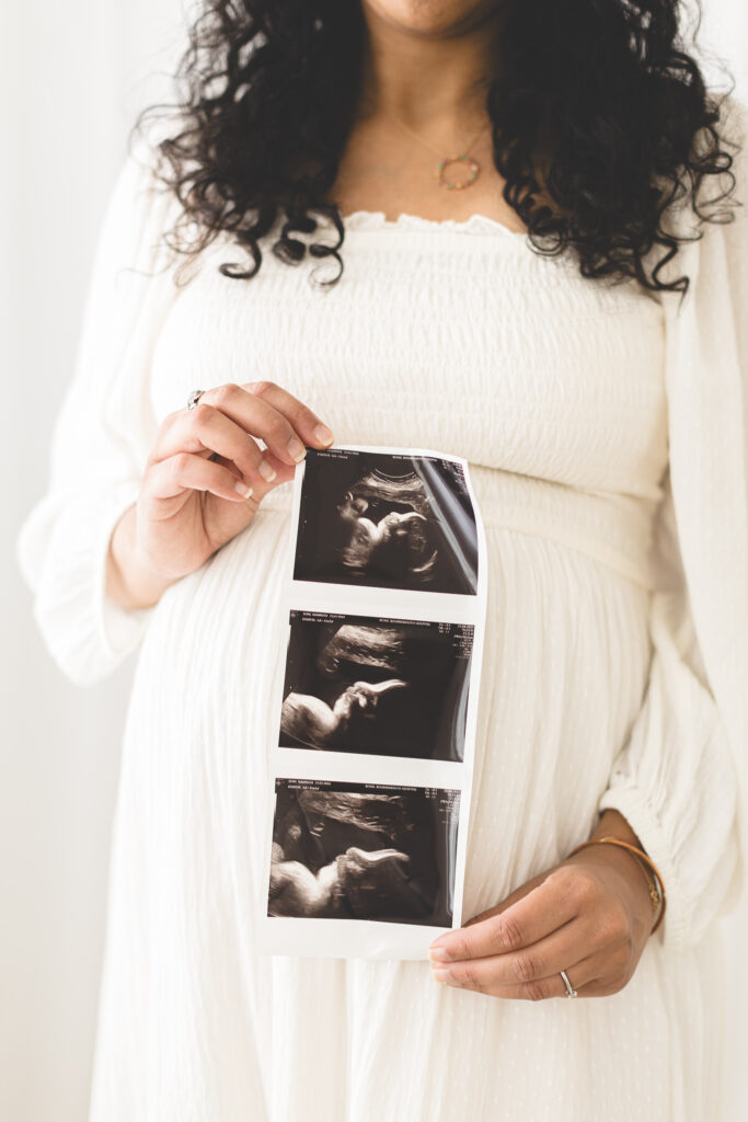 Pregnant lady holding scan photo in front of bump