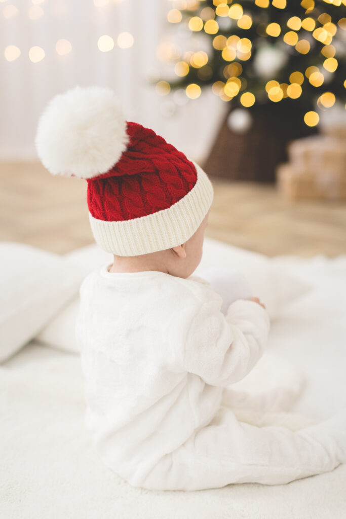 Santa hat on baby facing Christmas tree