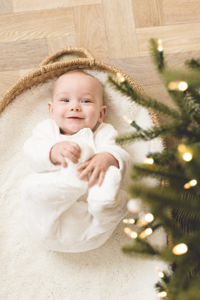 Baby under Christmas tree holding his feet