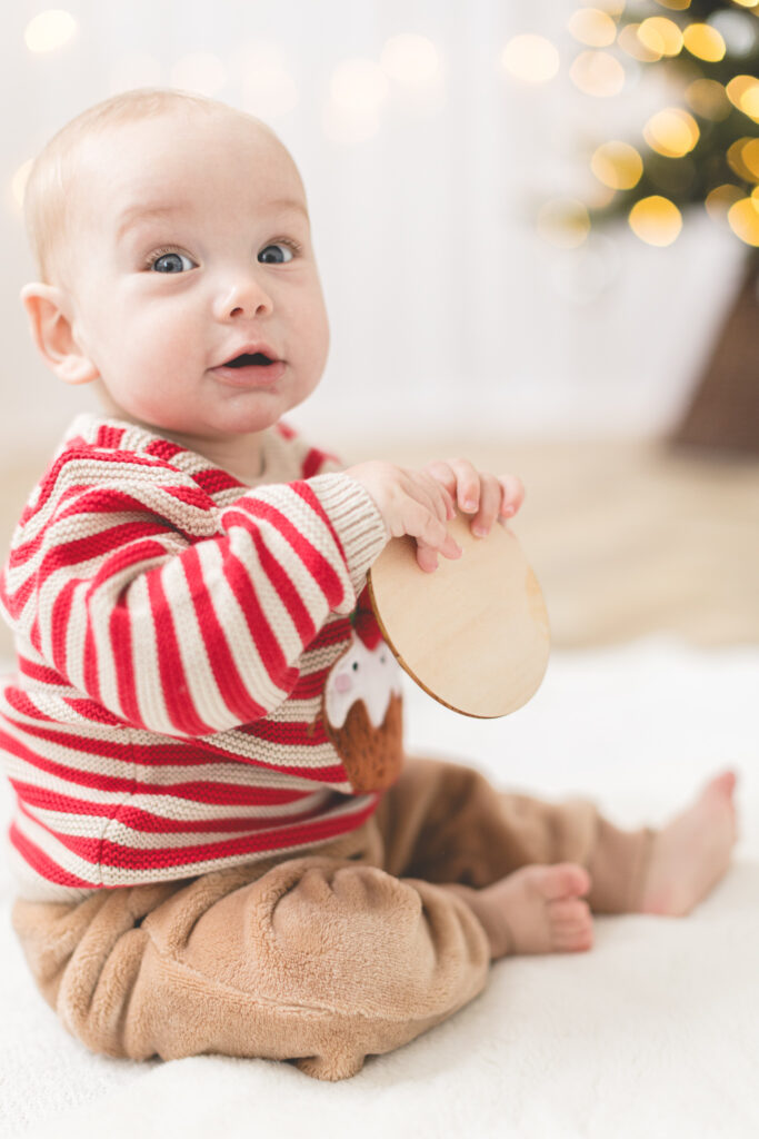 Baby with red stripey Christmas jumper with christmas lights