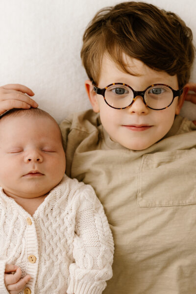 Newborn baby brother and big brother looking to camera
