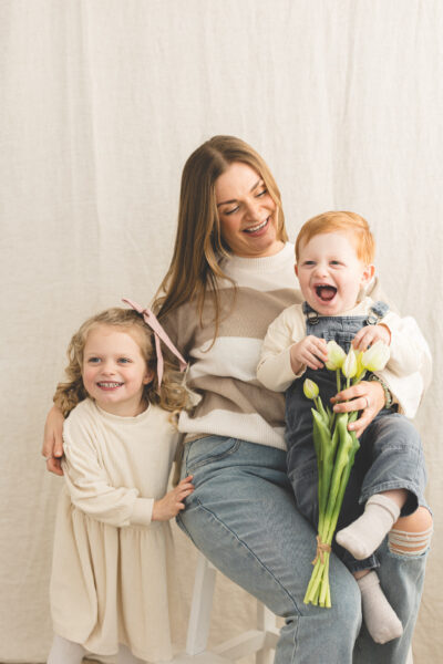 Mum with two children and a bunch of tulips. Baby has a big smile